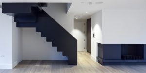 This image shows the open plan loft area with the black metal stairs and fireplace of this 1888 office conversion to luxury loft spaces in Soho, London.