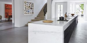 This image shows the refurbishment of the Little Venice, London historic property. It is the view of the refurbished staircase leading down to the new kitchen on the lower ground floor. This image shows the 8.5 metre long marble kitchen island. The floors are polished concrete and the walls are plain white to enhance the paintings. This image exemplifies our modern approach to the design and refurbishment of historic properties in Europe.