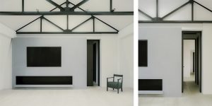 This images shows the living area with the restored black trusses, the fireplace and entrance to the bedrooms in the loft apartment.